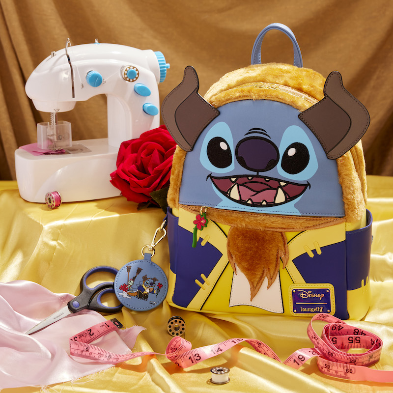 Loungefly Stitch in Beast Costume Exclusive Cosplay Mini Backpack sitting on golden-colored satin beside a sewing machine, scissors, and a tape measure.